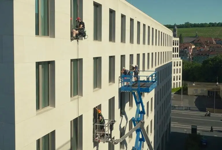 Höhenreinigung an Gebäudefassade mit Seilklettertechnik und Hubarbeitsbühnen